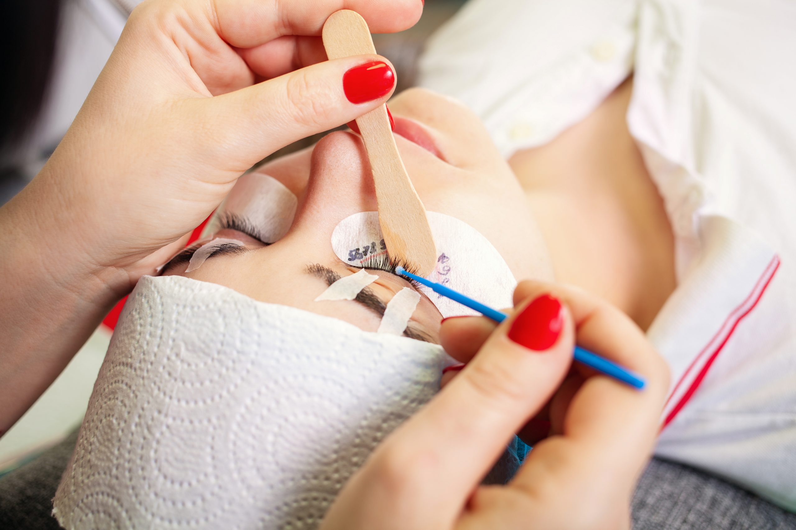 Preparation for eyelash extensions. Layout the patch on the size of the eyelashes. A young girl lies on a couch. Degrease eyelashes with a brush and alcohol.